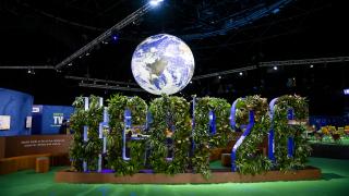 in a tv studio, a world suspended over the greenery covered letters COP26