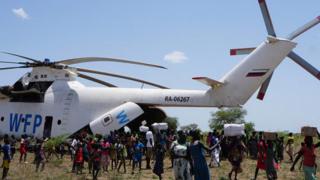 white helicopter with many people standing around it