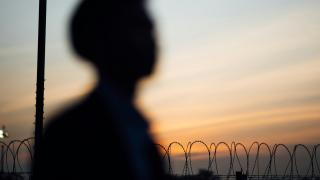 Person silhouetted against barbed wire fence