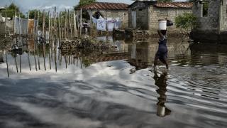 Photo: A woman carries supplies through a flooded street in Cap Haïtien.