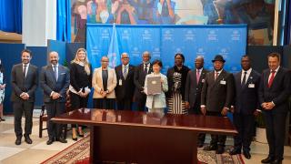 A group of state representatives stand together holding up the recently signed and ratified Treaty on the Prohibition of Nuclear Weapons in September 2022.