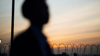 Person silhouetted against barbed wire fence